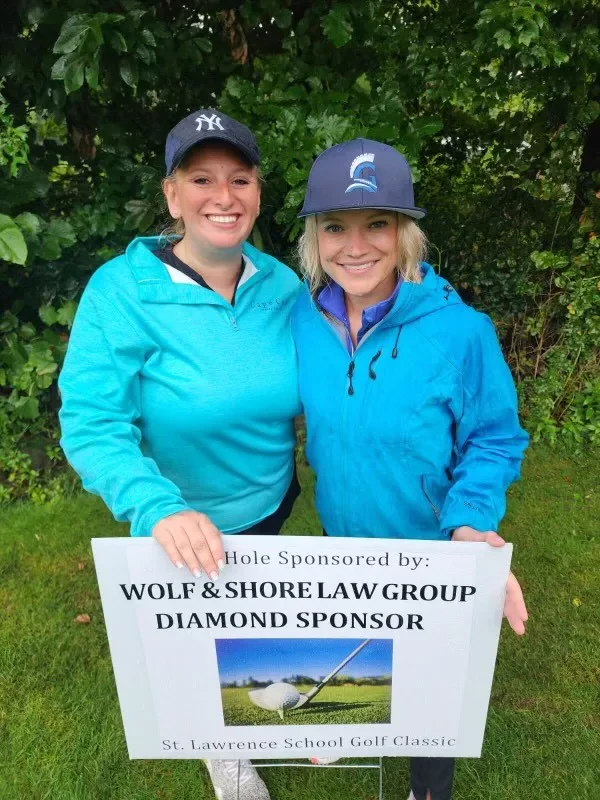 Wolf & Shore Law Group holding a Diamond Sponsor hole sign at the St. Lawrence School Golf Classic