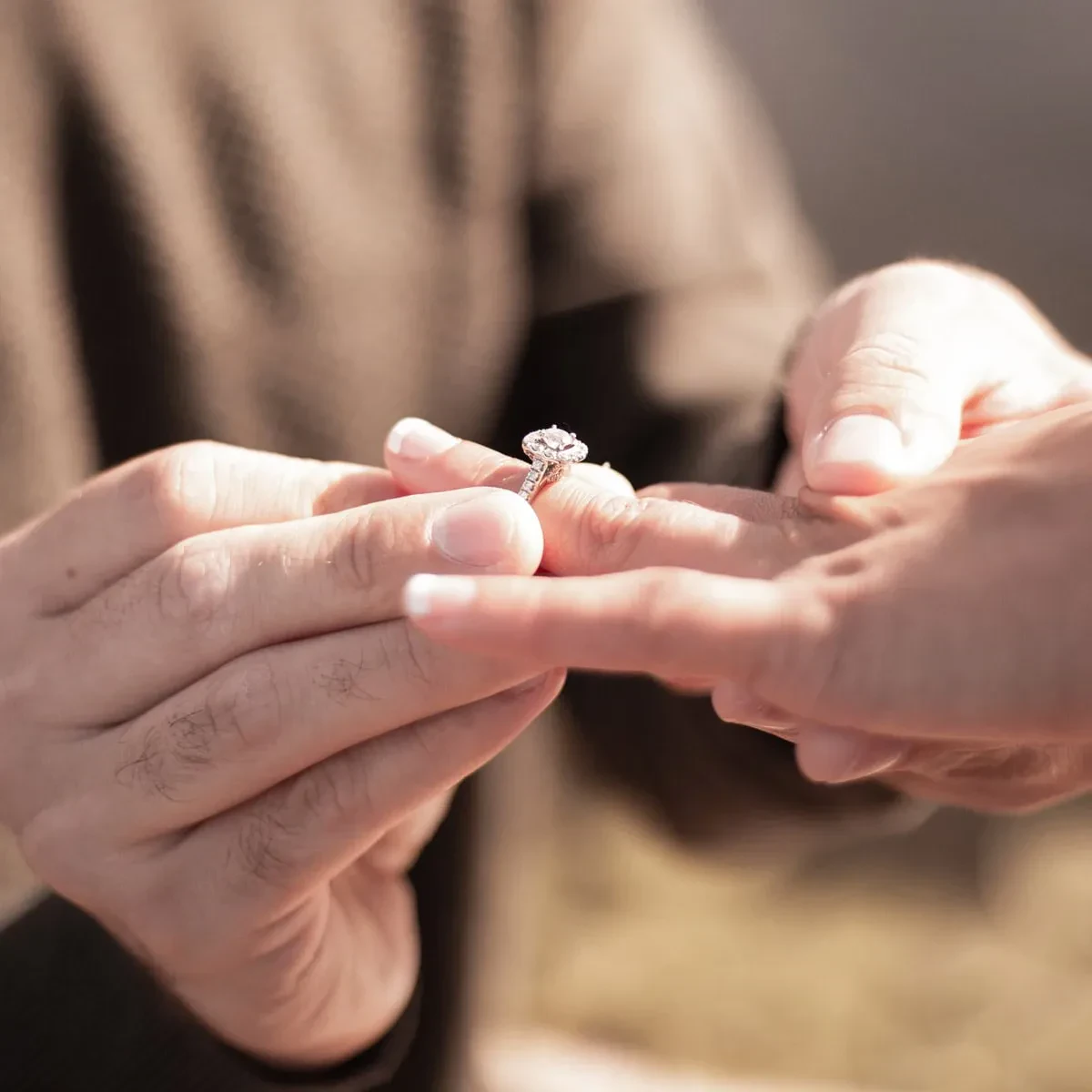 A man gently places a ring on a woman's finger during a proposal, capturing a moment of love and commitment