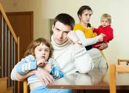 A family of four sits around a table in a living going through a difficult time.