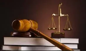 A wooden judge's gavel resting on a stack of law books, with a golden scale of justice blurred in the background.