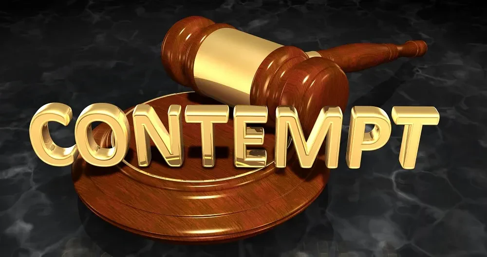A 3D rendering of a wooden judicial gavel and sound block sitting on a dark, textured surface, with the word "CONTEMPT" spelled out in large, metallic gold letters standing in the foreground.