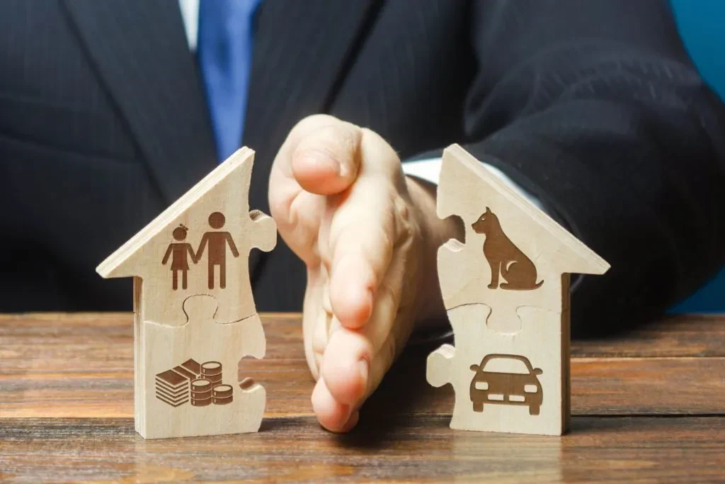 A man in a suit holds splits a wooden miniature house in two.