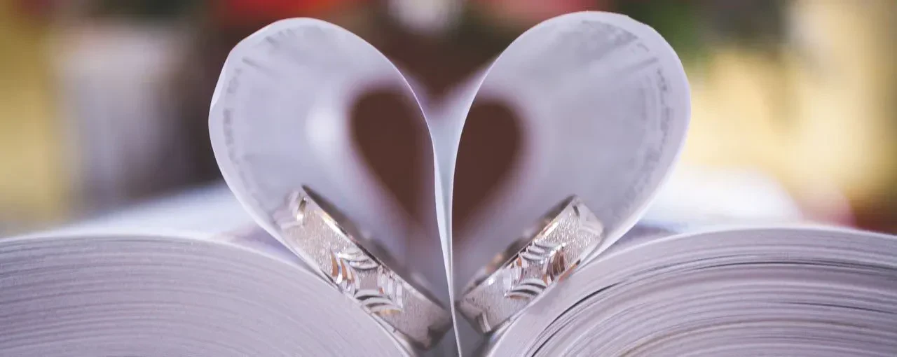 A pair of books with heart-shaped pages, with rings beneath the pages.