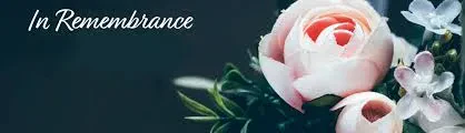 A soft pink rose bouquet with delicate white flowers set against a dark background, featuring the elegant white cursive text In Remembrance in the top left corner.