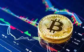 A gold Bitcoin coin rests on a screen displaying colorful financial graphs and charts, symbolizing cryptocurrency market trends and analysis.