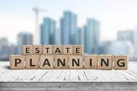 Small wooden alphabet toy blocks arranged to spell out the words ESTATE PLANNING on a rustic white table with a blurred city skyline backdrop.