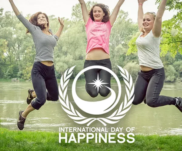 Three women joyfully jumping with the International Day of Happiness logo in the background, celebrating positivity and joy.