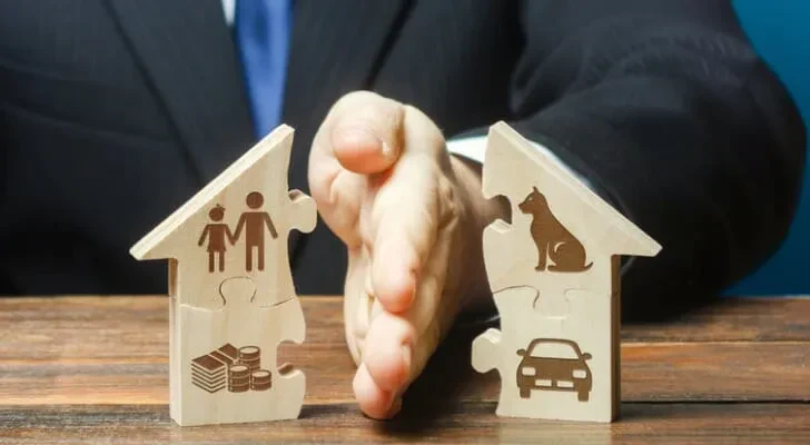 A man in a suit splits a miniature wooden house in half.