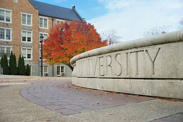 The University of North Alabama, specifically featuring the historic brick architecture of Wesleyan Hall and the "University" stone fountain.