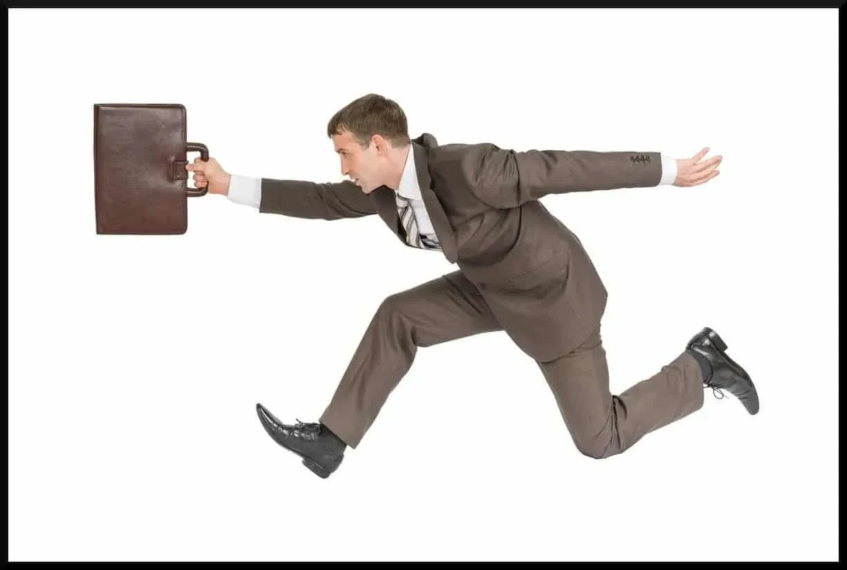 A man in a brown suit holding a brief case running.