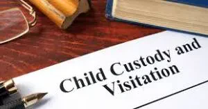 A document titled Child Custody and Visitation sits on a desk next to a book, eyeglasses, and a wooden gavel.