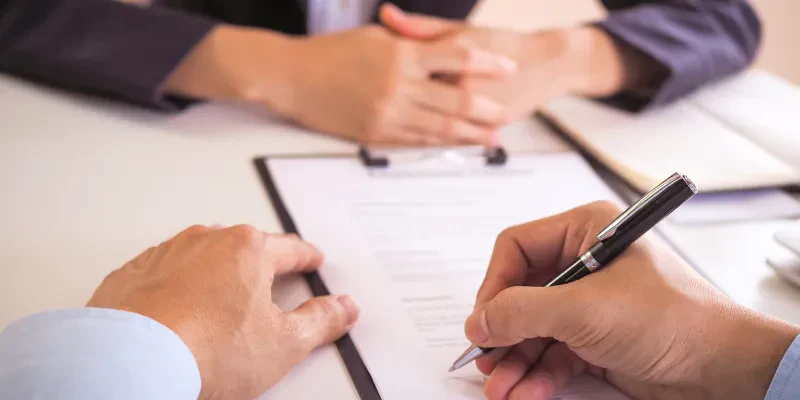 An elegant black and silver executive rollerball pen held in a person's right hand while signing a document.