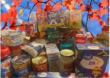 A table featuring a box of food, complemented by scattered autumn leaves.