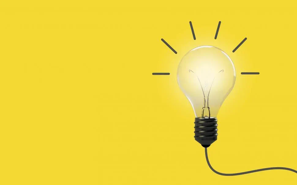 A light bulb illuminated against a bright yellow background, symbolizing ideas and creativity.
