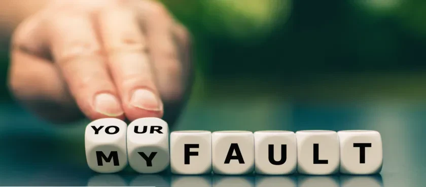 A hand modifies a row of white letter blocks to change the phrase "YOUR FAULT" to "MY FAULT" by flipping the first two cubes.