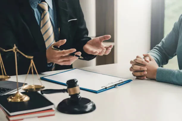 A lawyer and client converse intently, reviewing case details in a professional office environment.
