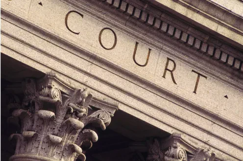 A close-up shot of the Supreme Court of the United States exterior featuring the word "COURT" carved into the classical frieze above ornate Corinthian column capitals.