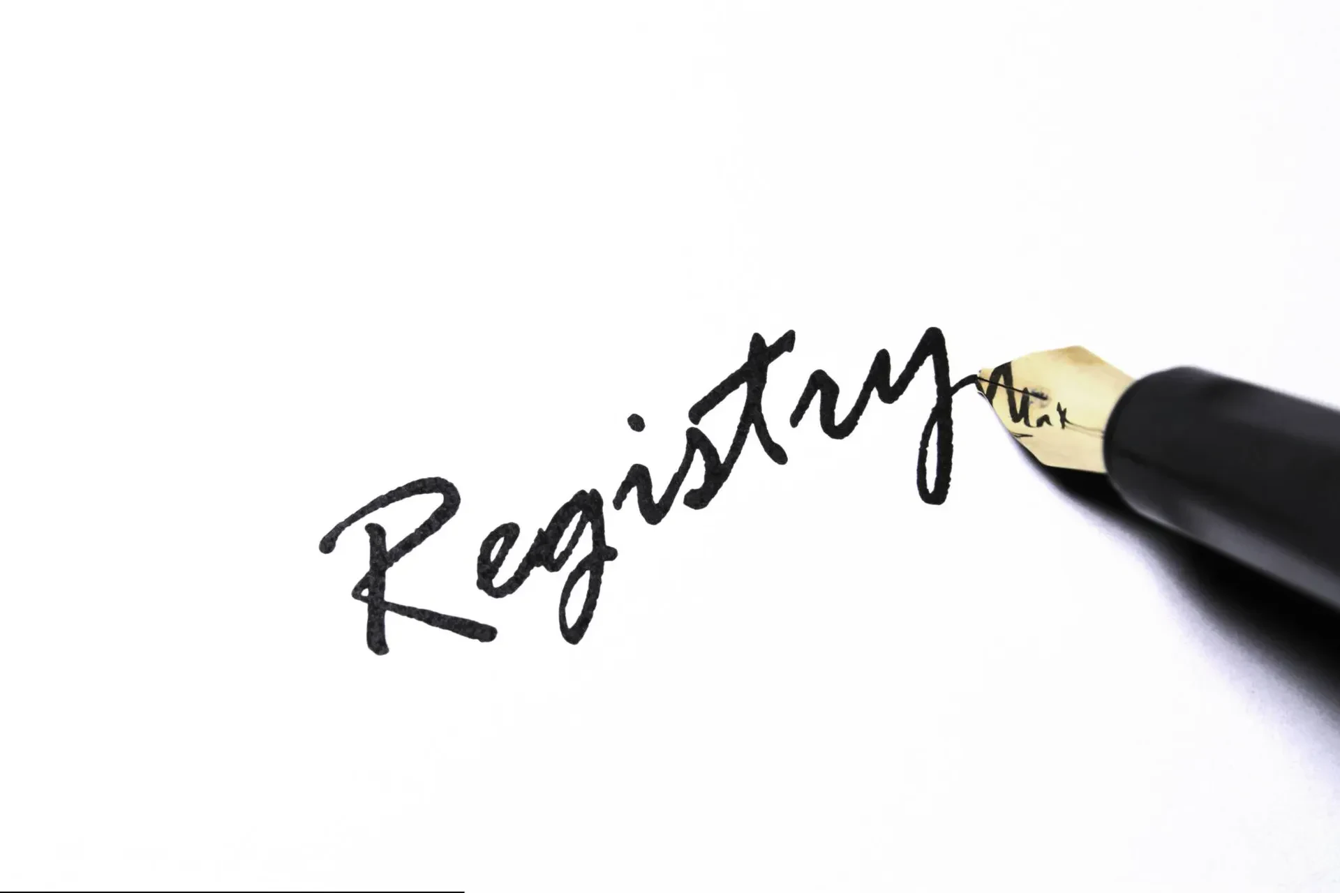 A fountain pen writing the cursive word "Registry" on white paper.