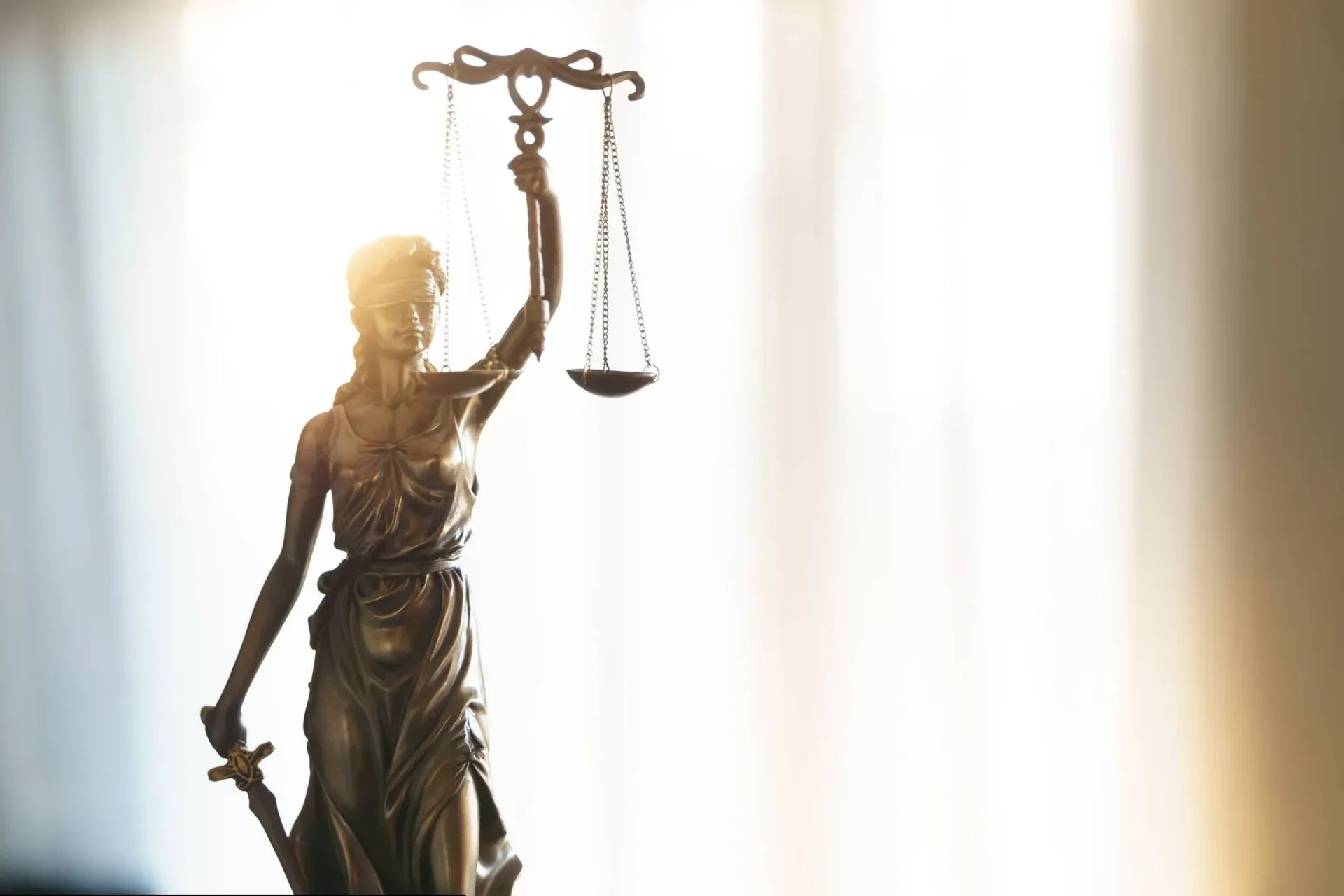 A statue of Lady Justice holding scales, symbolizing fairness and the legal system, set against a neutral background.