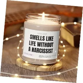 A candle in a clear glass jar with a white label that reads "SMELLS LIKE LIFE WITHOUT A NARCISSIST" in bold black text.