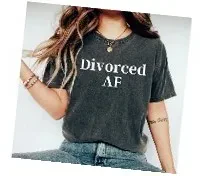 "A woman wearing a charcoal grey acid-wash graphic t-shirt that reads 'Divorced AF' in white serif font across the chest."