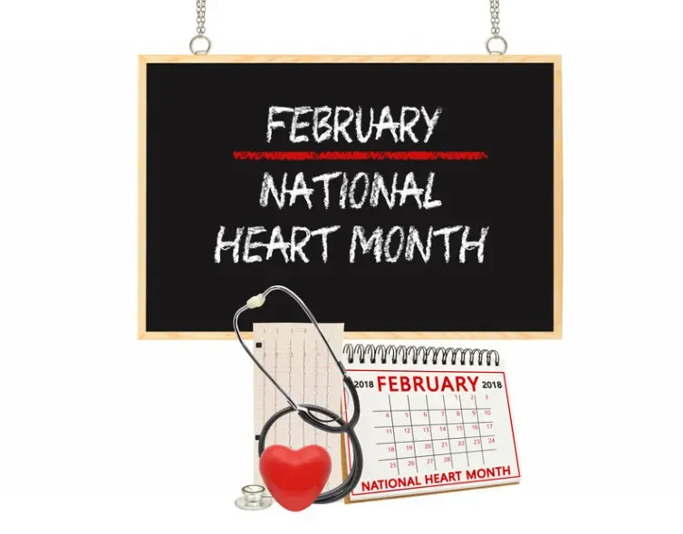 A chalkboard reads February National Heart Month above a calendar, EKG printout, stethoscope, and a red heart.