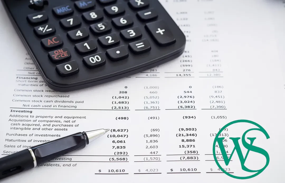 A black calculator sits at the top left over a financial spreadsheet detailing financing and investing cash flows.