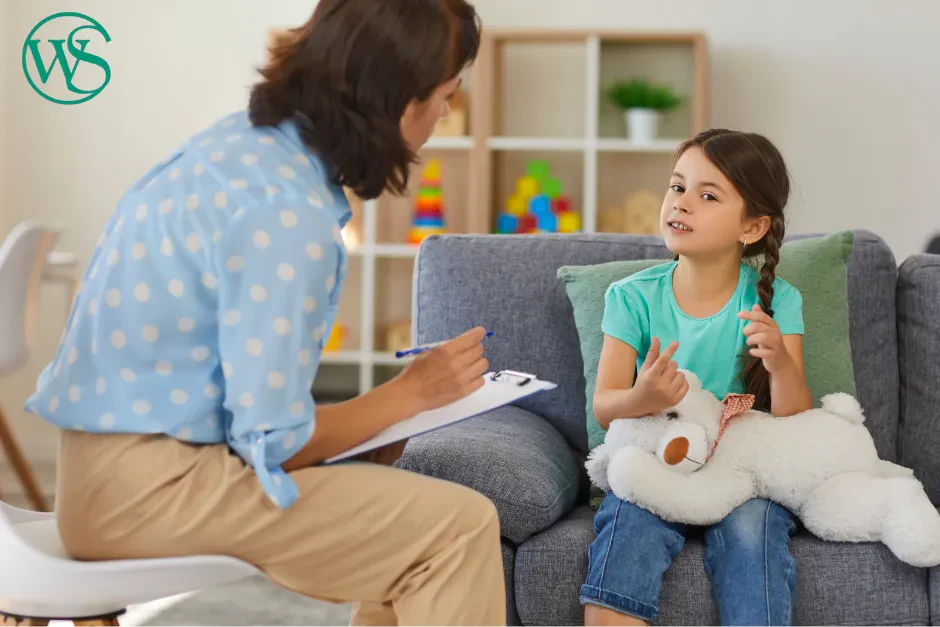 A woman speaks to a child, both seated in a warm and inviting living room.