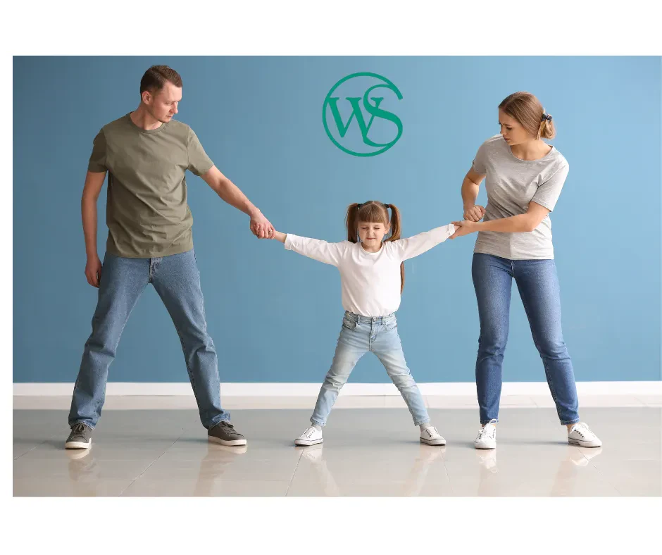 A child being tugged on both sides by her parents
