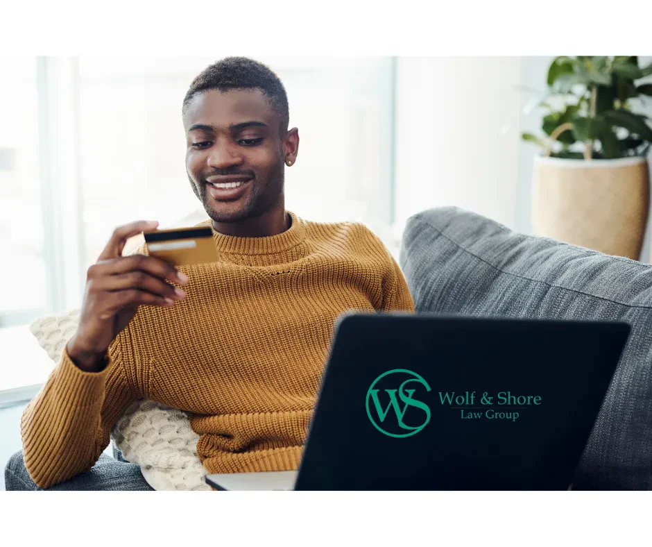 A man on his computer looking at his bank card.