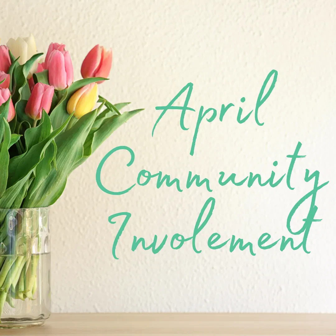 A glass vase of pink and yellow tulips sits on a wooden surface. The text on the right reads: April Community Involvement in green script.